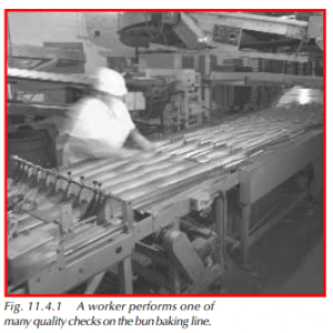 A worker performs one of many quality checks on the bun baking line.